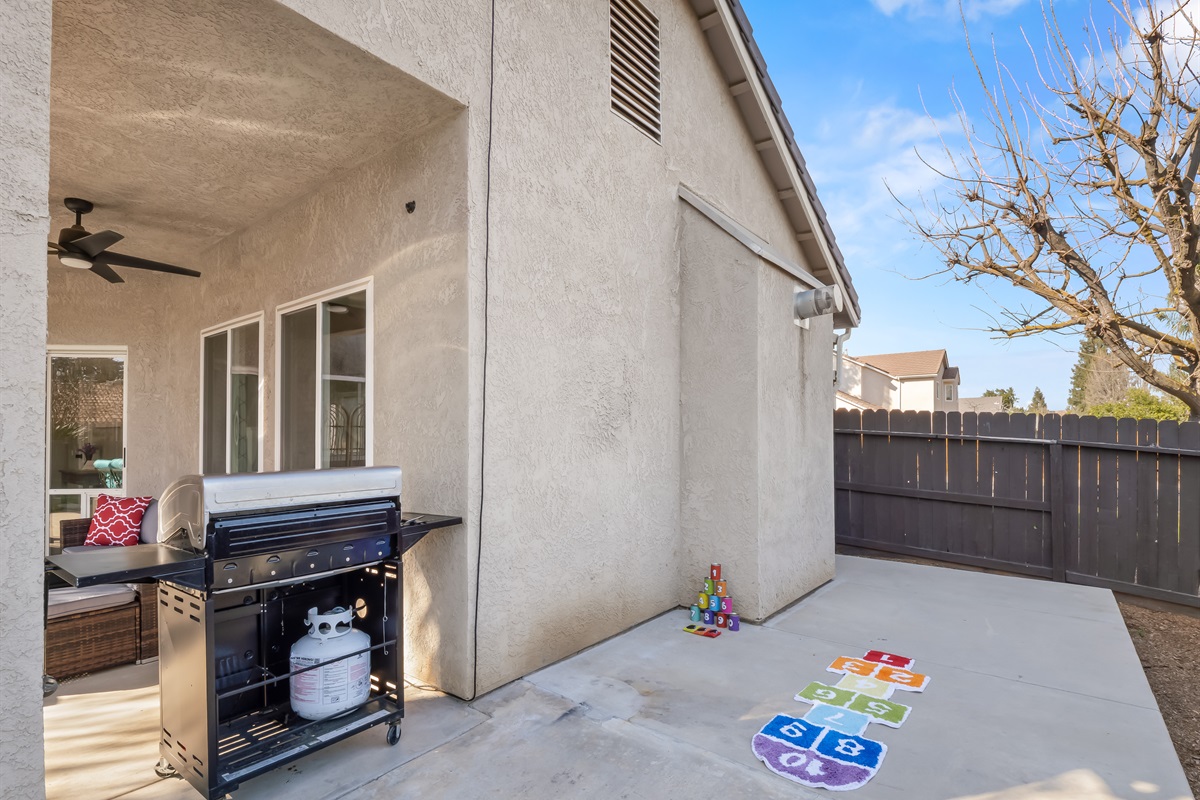 Open concrete space with hopscotch, lawn games, and room to run makes this yard perfect for little ones to burn off energy safely inside a fully fenced yard.
