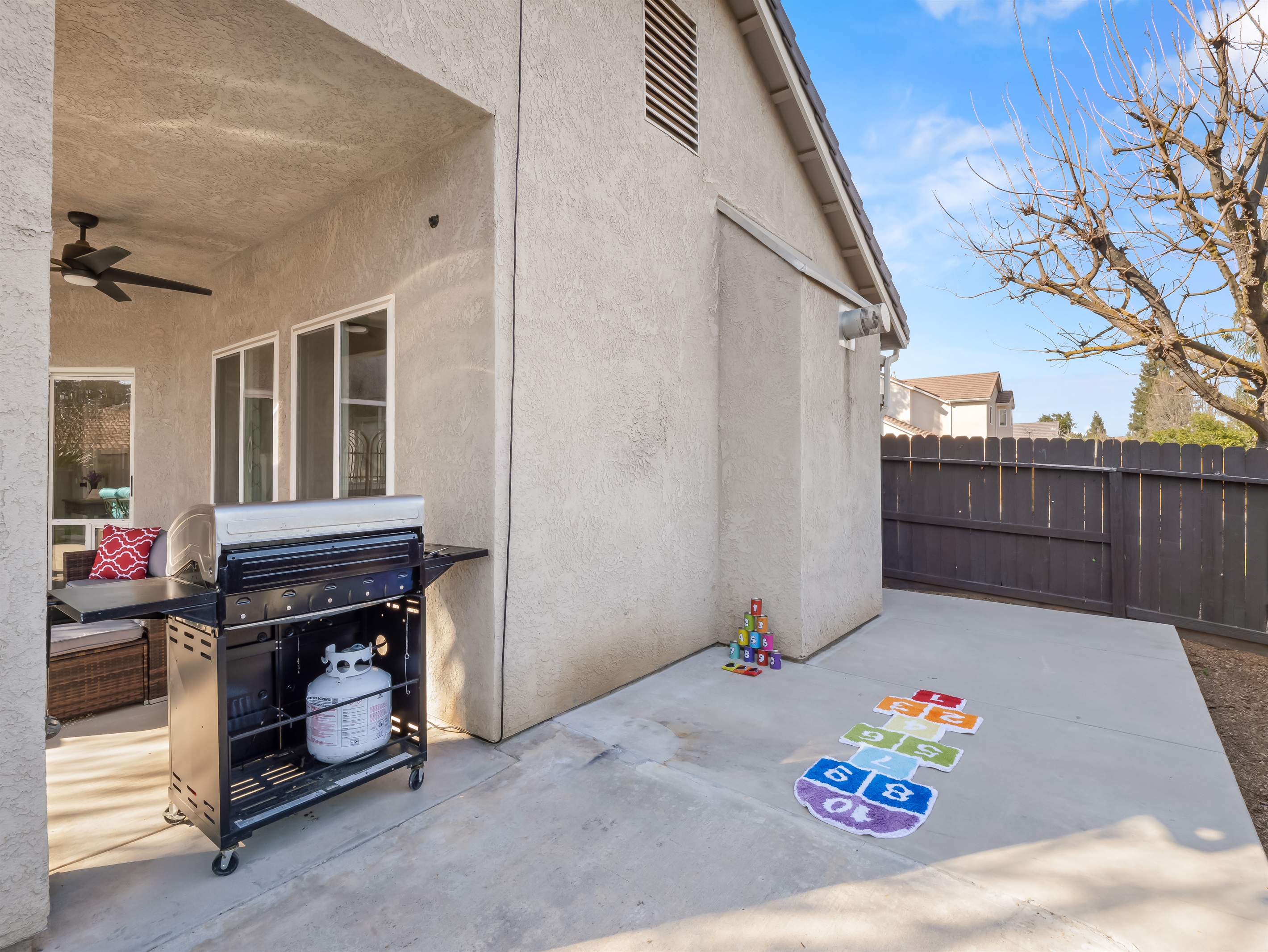 Open concrete space with hopscotch, lawn games, and room to run makes this yard perfect for little ones to burn off energy safely inside a fully fenced yard.