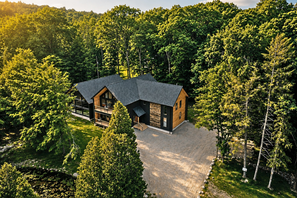 Aerial view: modern Scandinavian villa, built 2025, surrounded by tall trees. A wide paved drive welcomes the whole group.