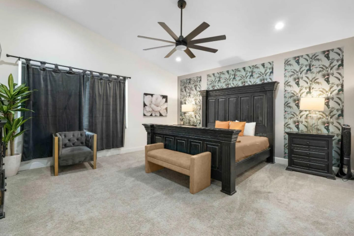 Luxe bedroom with statement black bed frame, botanical wallpaper, and spa-like seating area.