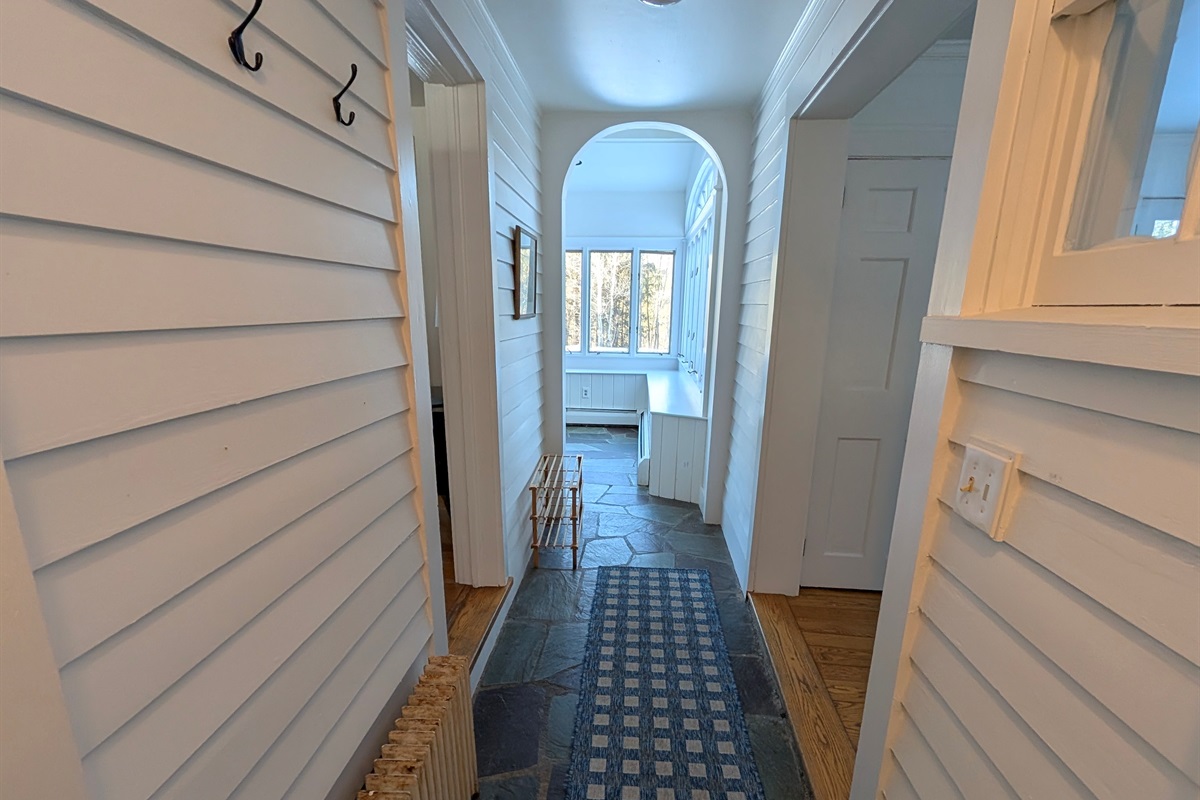 Light-filled hallway guides you toward the heart of the home, highlighted by classic arches and natural finishes.