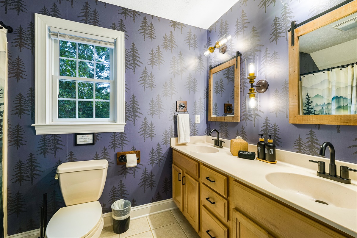 A whimsical bathroom with a nature-inspired wallpaper and double-sink vanity, perfect for families getting ready at the same time. Thoughtful touches like makeup towels, soft lighting, and quality toiletries add comfort and style.