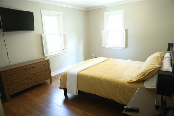 NE Bedroom showing Roku TV, dresser, queen size bed, nightstands with touch lamps and alarm clock