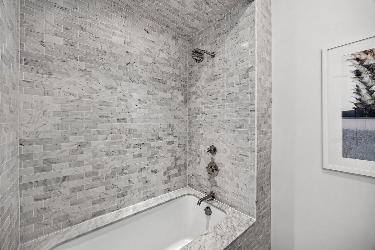 Guest Suite #1 Ensuite bath offers a deep soaking tub with marble surround.
