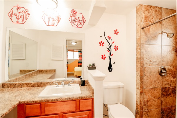 A spotlessly clean toilet complements the serene beauty of a wall adorned with floral designs, reflecting softly in a mirror that captures the essence of nature's tranquility. It's more than a space—it's a sanctuary for peaceful moments and self-care.