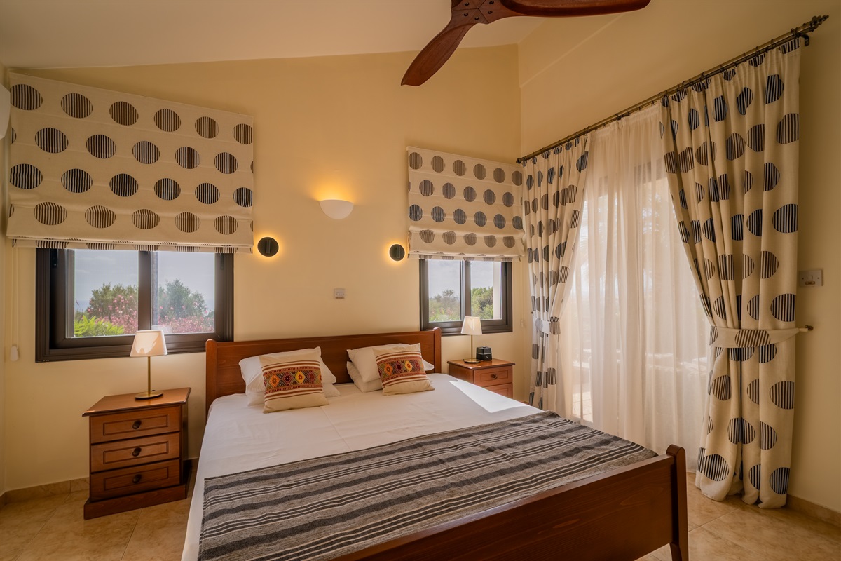Master king ensuite bedroom with sea views and terrace access. King size bed, ceiling fan, dedicated AC/heating unit, vanity, large built-in wardrobes, bluetooth speaker/alarm clock.