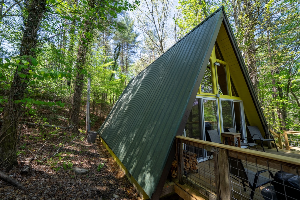 The classic A-frame design shines from the back, with large windows and a peaceful deck overlooking the trees.