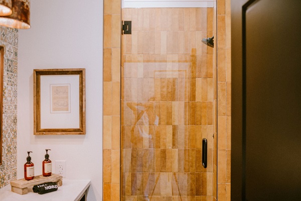 Walk-in tile shower at the Lazy Spur Suite &mdash; copper pendant lighting and warm modern Western finishes in your private en-suite bath.