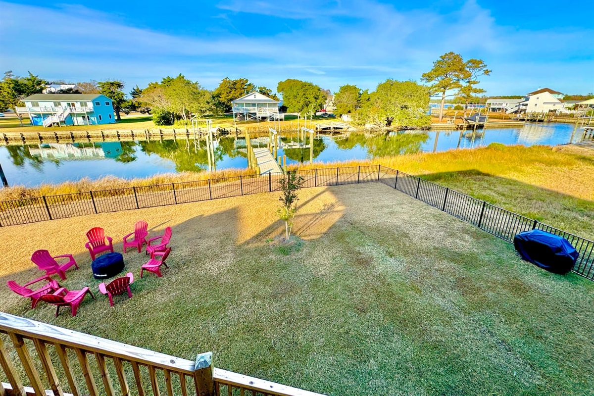 Private backyard dock with boat lift and fillet table, fenced-in backyard, fire pit with Adirondack chairs, hammocks, propane grill, picnic table, outdoor shower, expansive waterfront back deck with table and seating, neighborhood boat ramp and dock