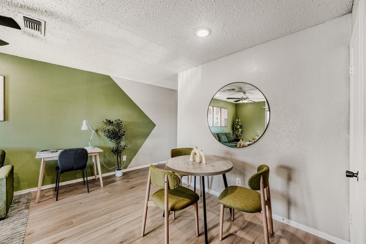 Cozy dining nook with green accents, modern furniture, and a stylish geometric wall design.
