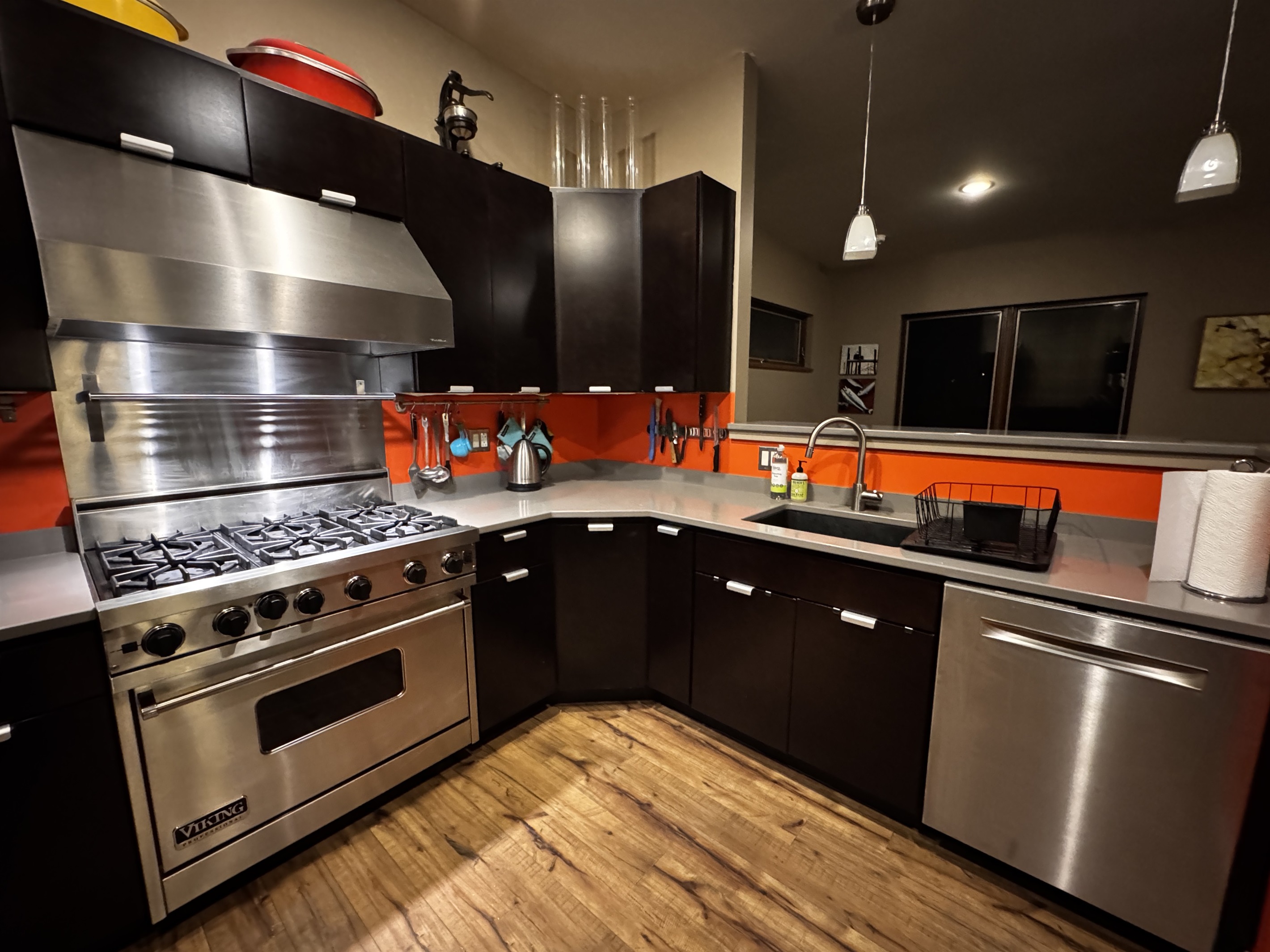 Functional kitchen layout featuring a stainless steel dishwasher and deep sink. The open pass-through looks directly into the dining area, keeping the group connected between meal prep and dinner at this modern Acadia retreat.