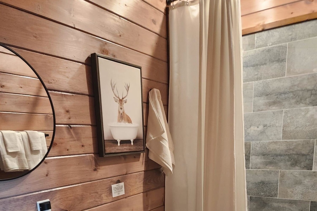 Full bathroom with round mirror, shelf space, and tasteful decor.