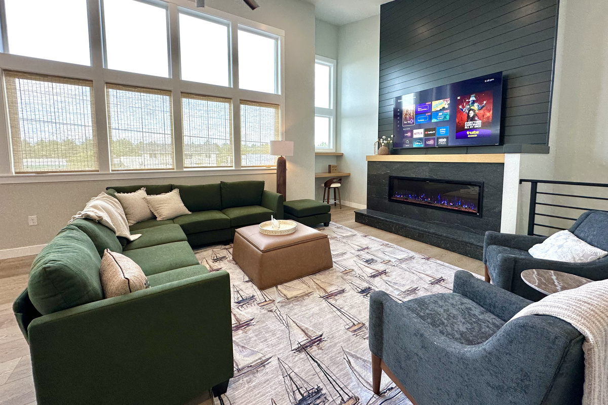 Wake up to sunlight pouring through two stories of windows — this is the other half of Side A's living space, fireplace glowing on the far wall.