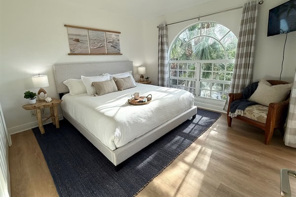 King size bed, oversized window provides views of the property's lush palm-lined paradise