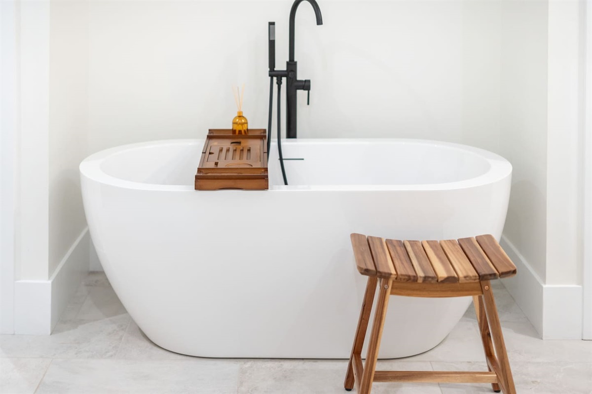 Freestanding soaking tub with bamboo caddy and spa stool for ultimate relaxation.