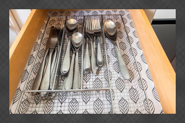 Stainless steel forks, knives, and spoons set neatly in a lined drawer for easy access during mealtime.