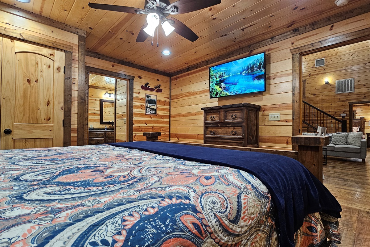 Bedroom 1: Relax in rustic charm with a plush bed and nature views through sunny windows!