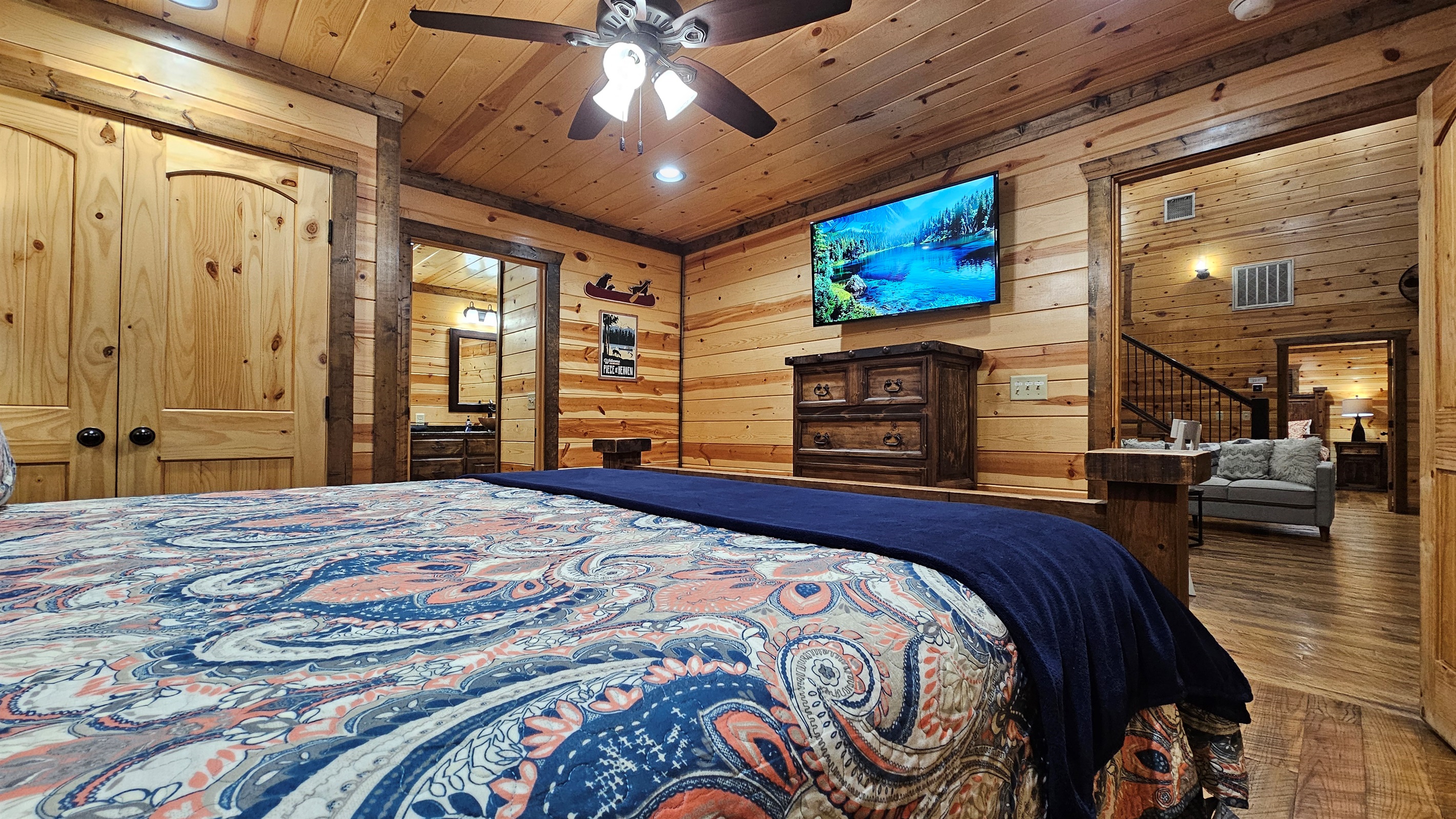Bedroom 1: Relax in rustic charm with a plush bed and nature views through sunny windows!