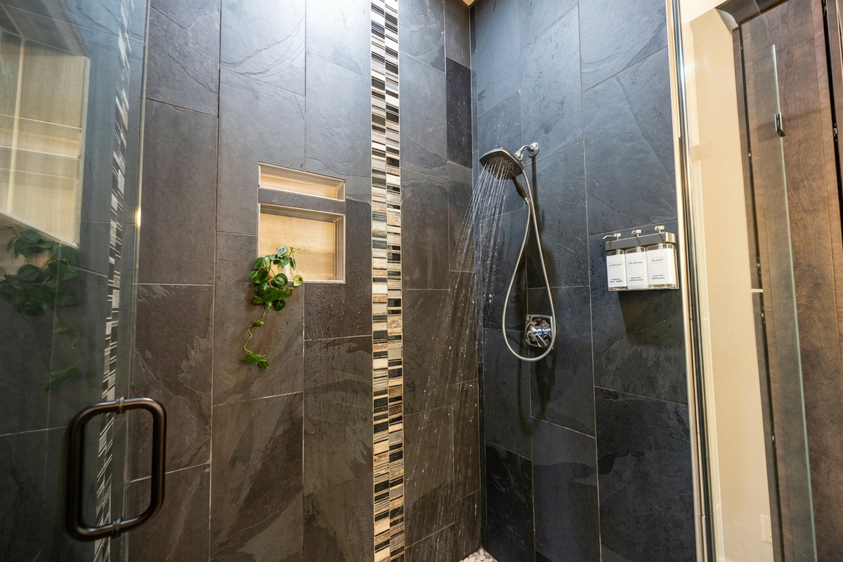 Oversized shower with floor to ceiling tile, large shower head and hand shower. Shower gel, shampoo and conditioner provided.