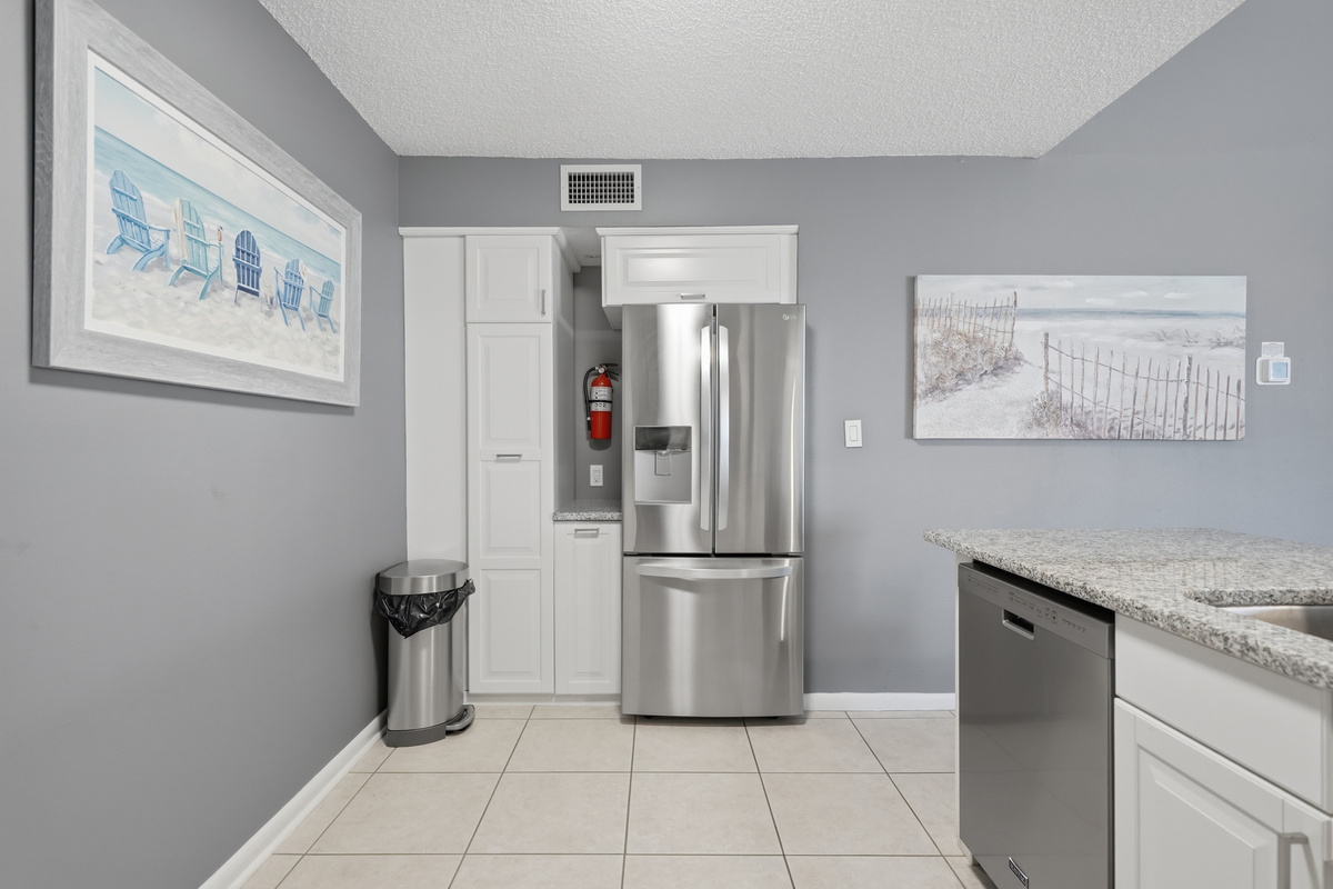 The fully equipped kitchen features stone countertops, solid wood cabinets, and modern appliances, including a refrigerator, range/oven, microwave, dishwasher, and garbage disposal. Everything you need to prepare meals.