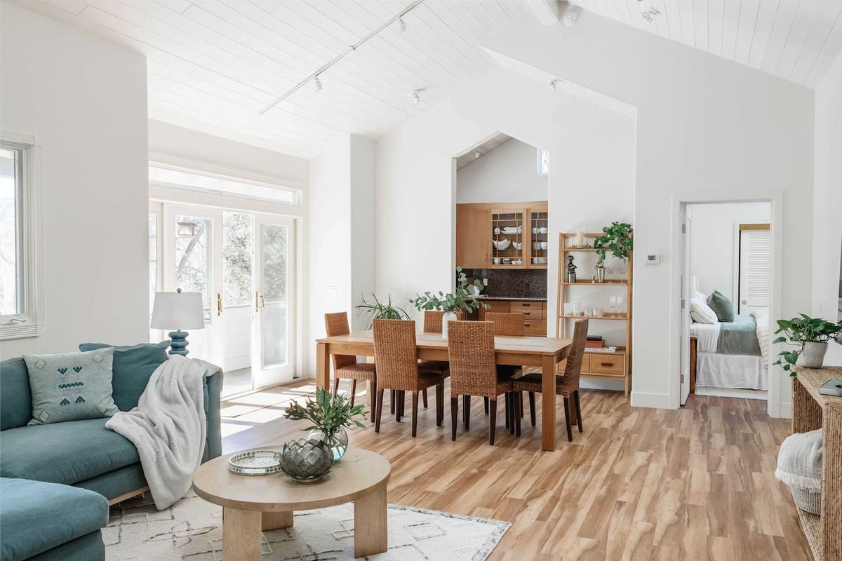 Open floor plan featuring hardwood floors, high ceilings, skylights, and abundant natural light. Enjoy designer décor, spacious seating, and seamless flow from the kitchen to the dining / living areas. Sliding glass doors lead to a covered deck 