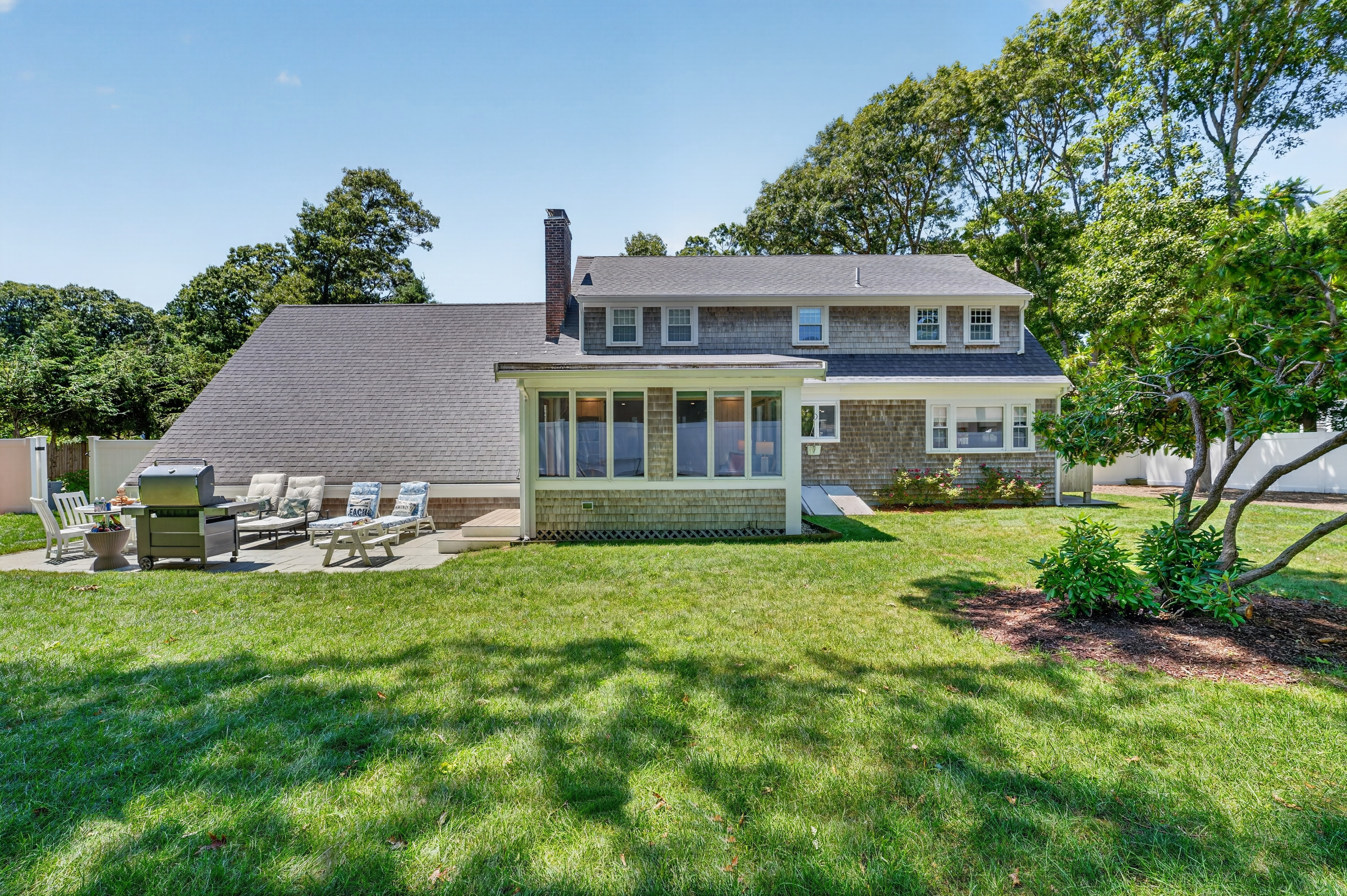 Rear view of the home showcasing the sunroom, patio, and private backyard.
