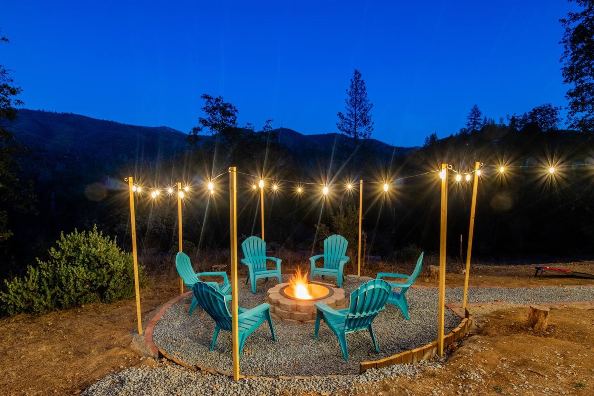 As the flames flicker, the surrounding mountains stand as majestic silhouettes against the night sky, turning the outdoor space into a serene retreat.