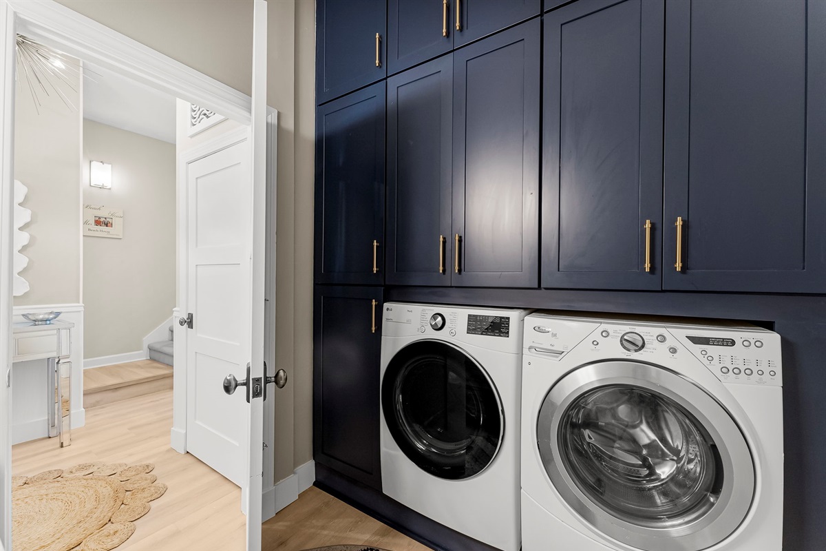Convenient half bath paired with a full-size washer & dryer and custom ceiling-to-floor cabinets complete with all your laundry essentials.