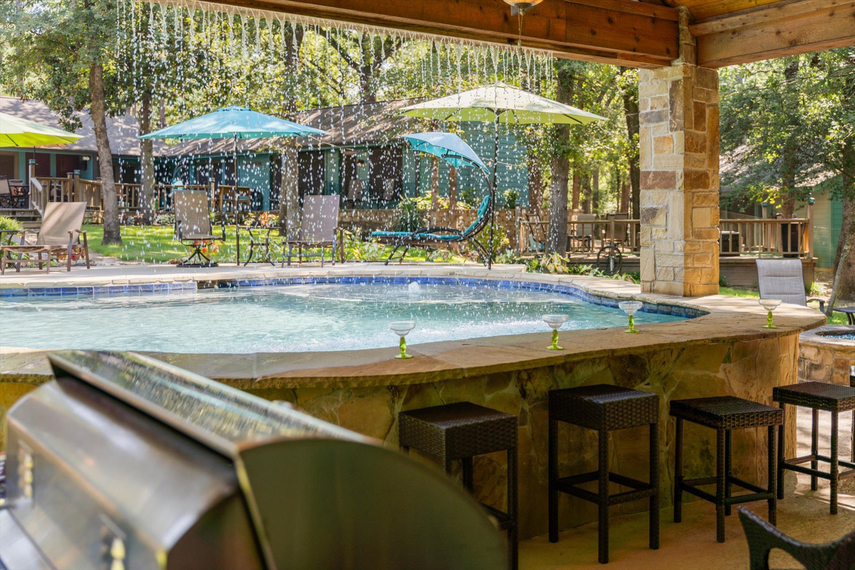 The rain curtain and the swim-up seats in the pool. These features add elegance and fun, creating the perfect spot to relax and enjoy the water while staying cool under the gentle cascade of the rain curtain.