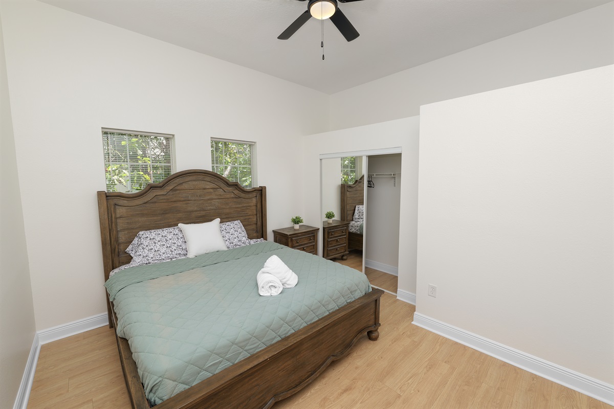 Unwind in timeless style—this spacious bedroom offers a king bed, wood furnishings, and soft lighting for a perfect night’s sleep.