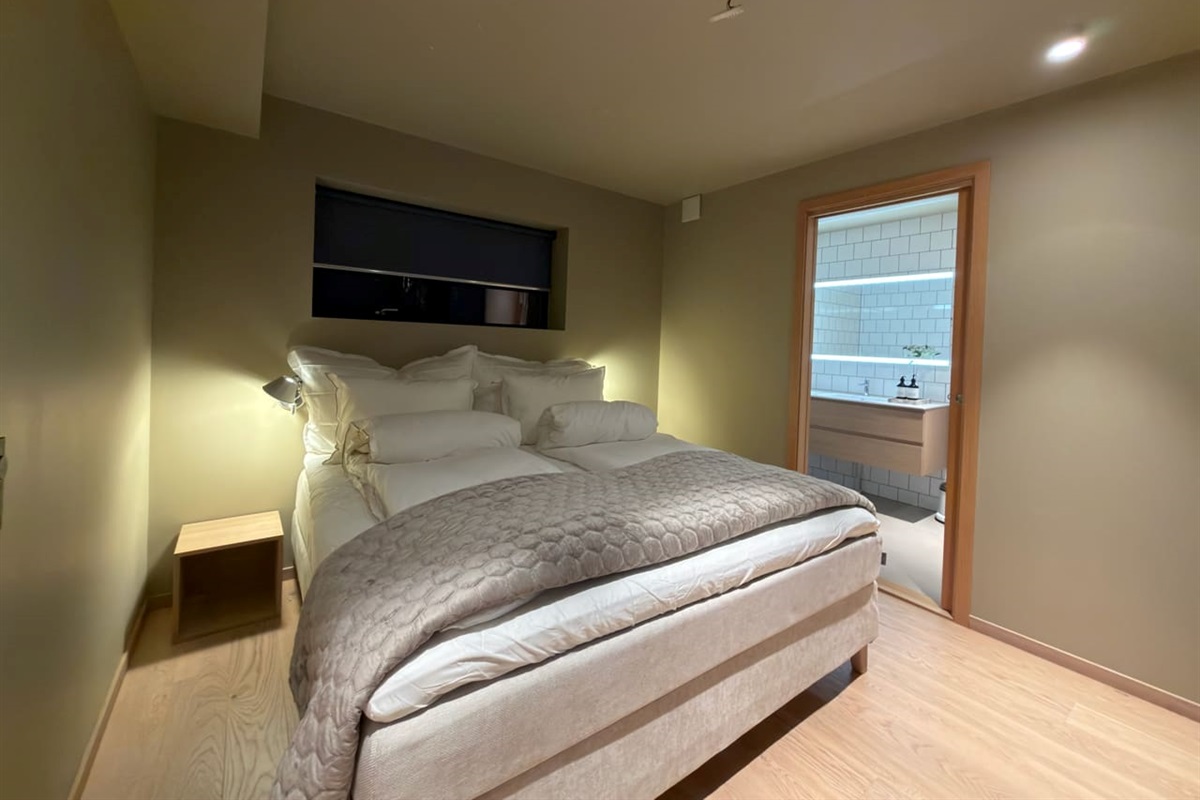 Bedroom with big high end bed and enclosed bathroom with bathtub