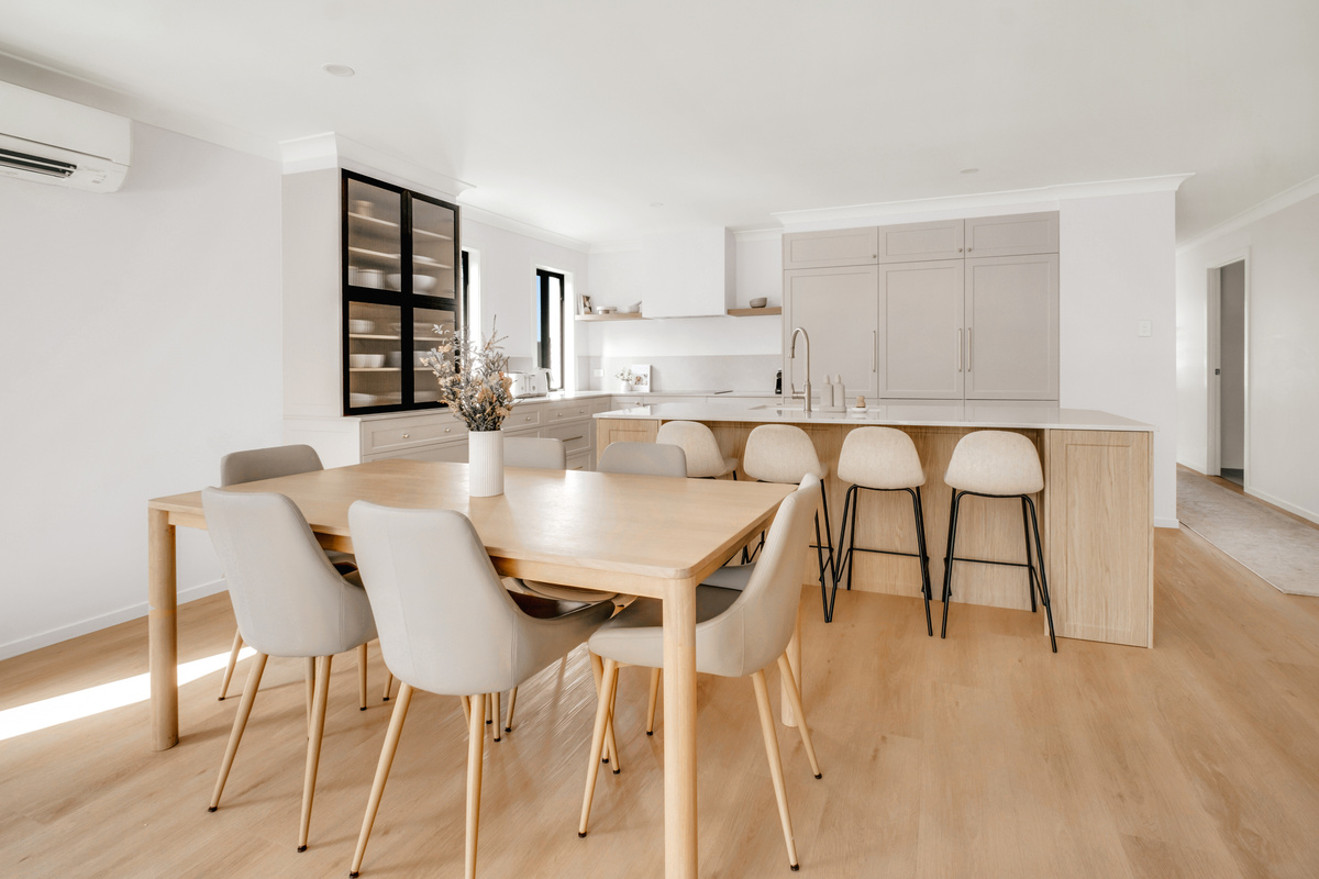 A welcoming dining space featuring warm timber finishes, comfortable seating and a beautifully designed kitchen island.