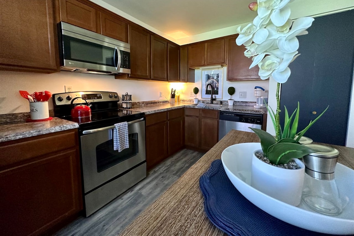 Modern kitchen with stainless steel appliances, spacious counters, and thoughtful details—like a central dining table with decor and essentials. Whether cooking, snacking, or gathering, this space is both functional and inviting for any stay.