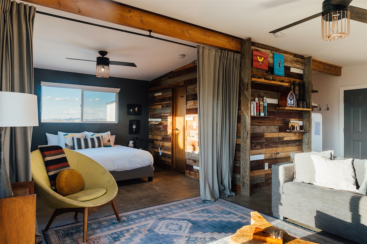 Open-concept layout showing the inviting bedroom from the living area, blending rustic design with natural desert light.