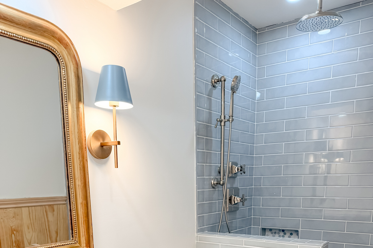 Stylish guest bathroom featuring blue subway tiles, a rainfall shower, and vintage-inspired finishes.