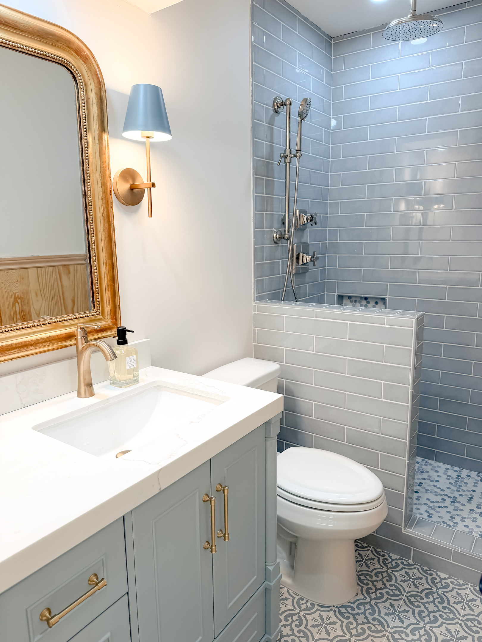 Stylish guest bathroom featuring blue subway tiles, a rainfall shower, and vintage-inspired finishes.