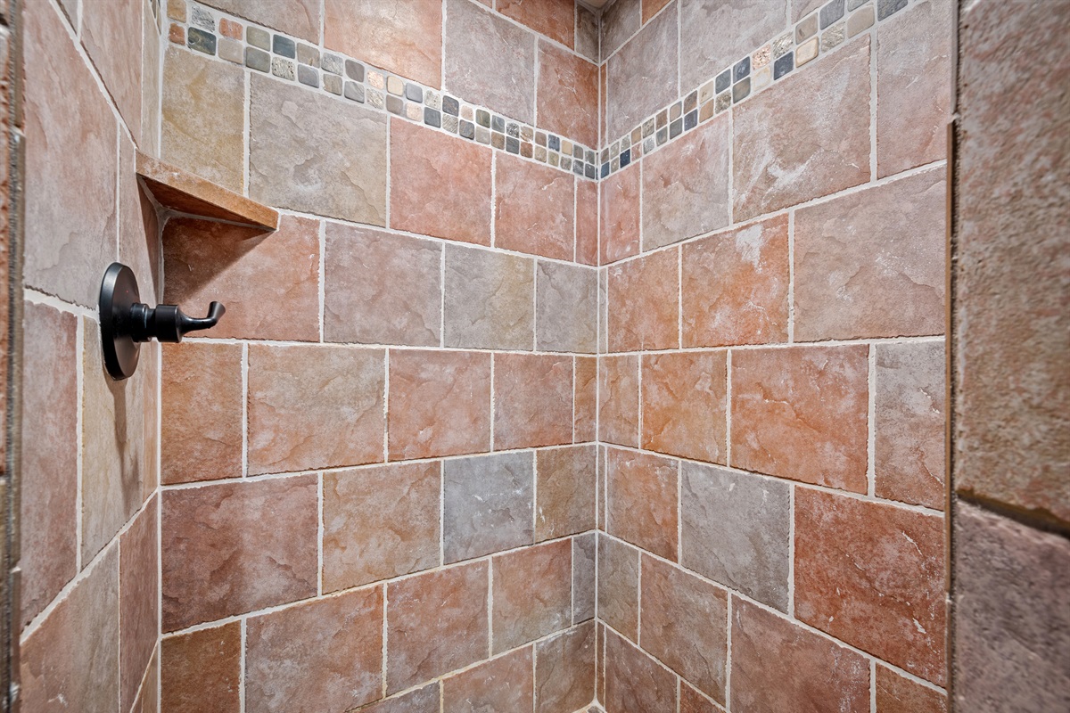 Earth-toned tile and built-in shelving make this shower both stylish and convenient.