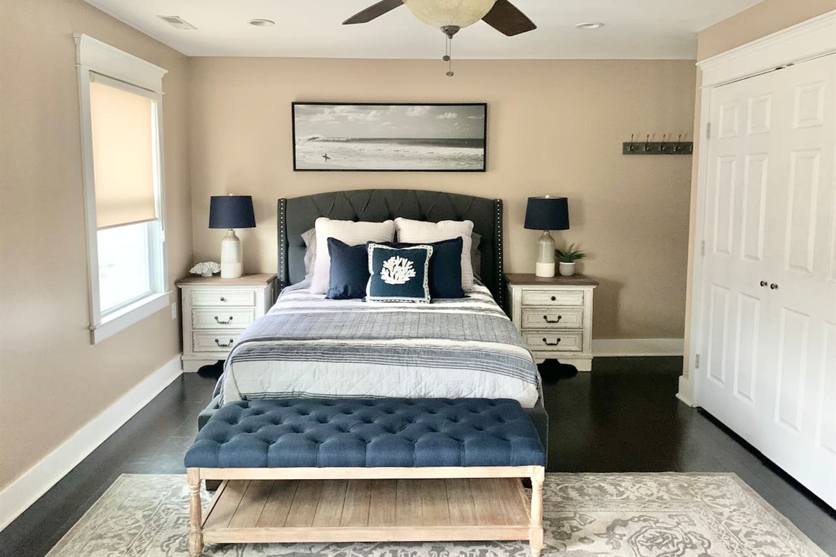 Relax in this bright, modern bedroom featuring a comfortable bed, stylish tufted bench, and coastal decor. This well-appointed area includes ample storage and calming tones, making it easy to enjoy a restful night before heading to the beach.