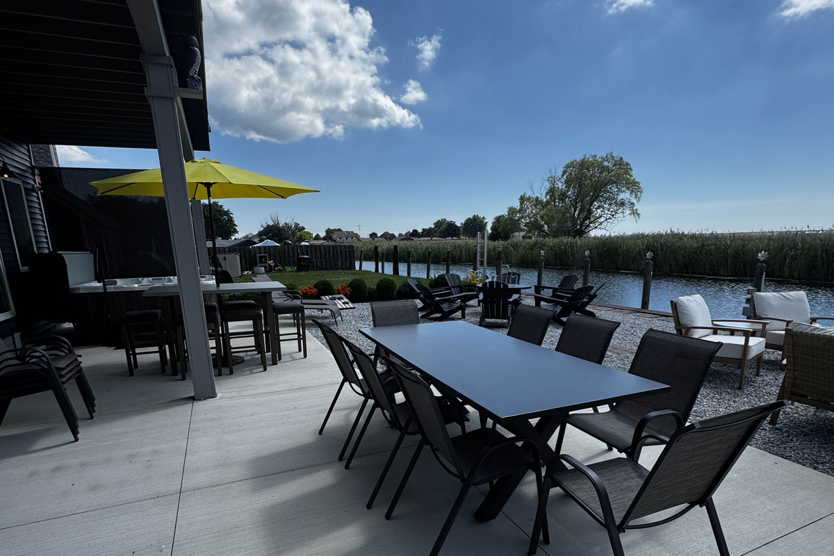 Spacious waterfront patio with outdoor dining and lounge seating, perfect for relaxing and entertaining by the canal.