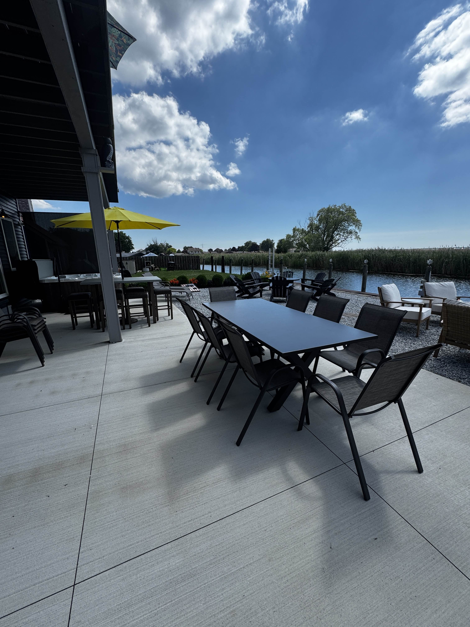 Spacious waterfront patio with outdoor dining and lounge seating, perfect for relaxing and entertaining by the canal.