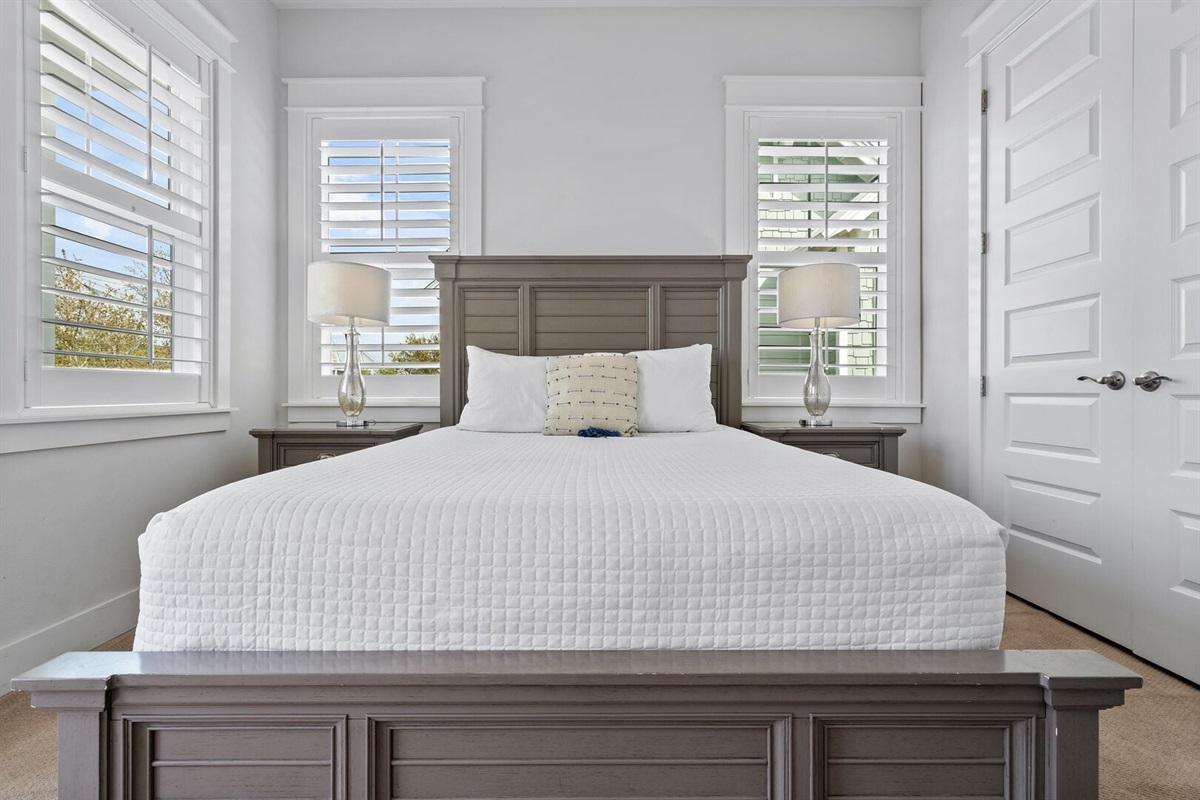 Primary bedroom with king bed and plantation shutters.