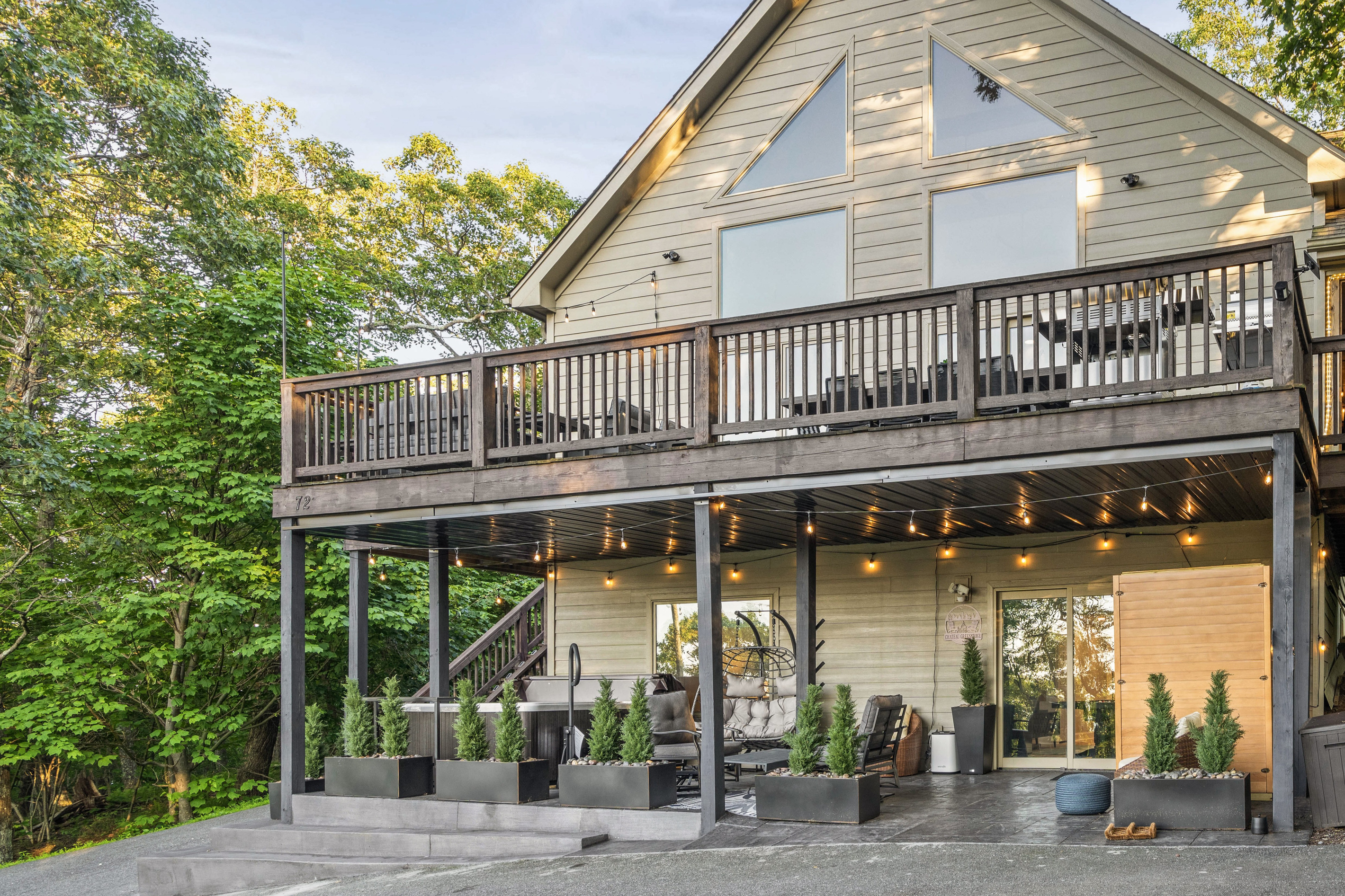 The lower patio extends the wellness vibe outdoors, with the hot tub, cozy seating, soft evening lights, and covered comfort all tucked beneath the main deck — an easy place to soak, unwind, and let the mountain air do its work.
