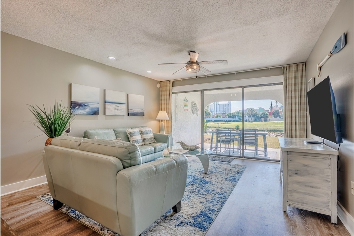 Living area with patio access, ceiling fan, and smart TV