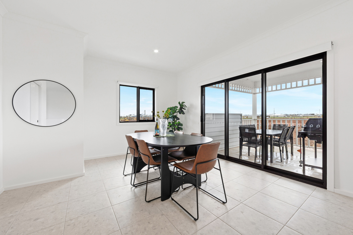 Dining table with chairs beside the sliding doors to the balcony, open to the kitchen and living area.