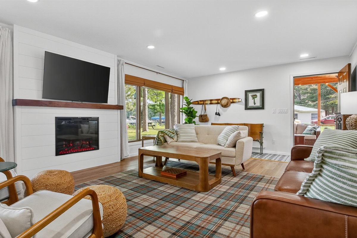 The bright living room has cozy seating, a large Roku TV, and lake views.