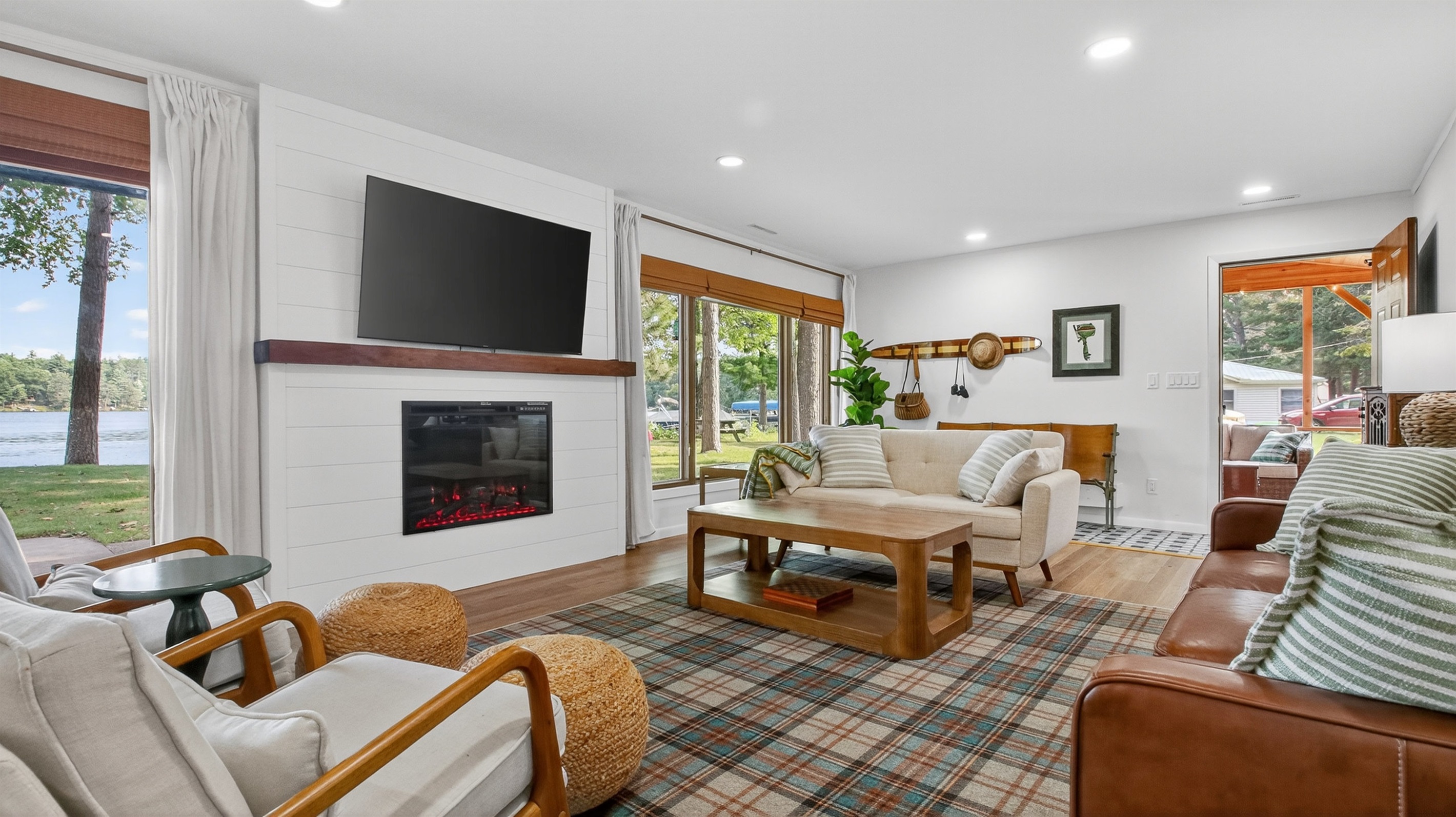 The bright living room has cozy seating, a large Roku TV, and lake views.