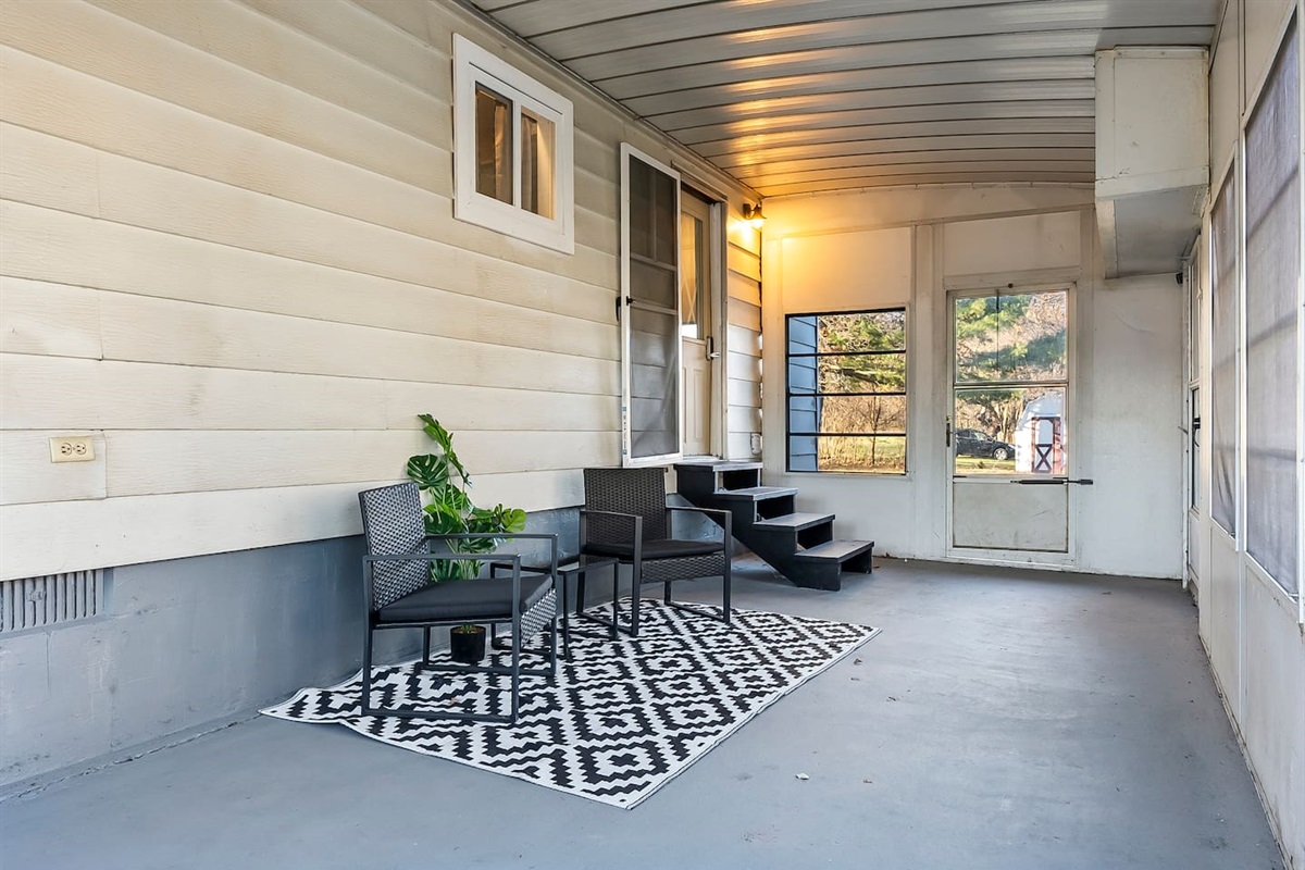 Covered porch with cozy seating and a patterned rug, perfect for morning coffee or evening relaxation.
