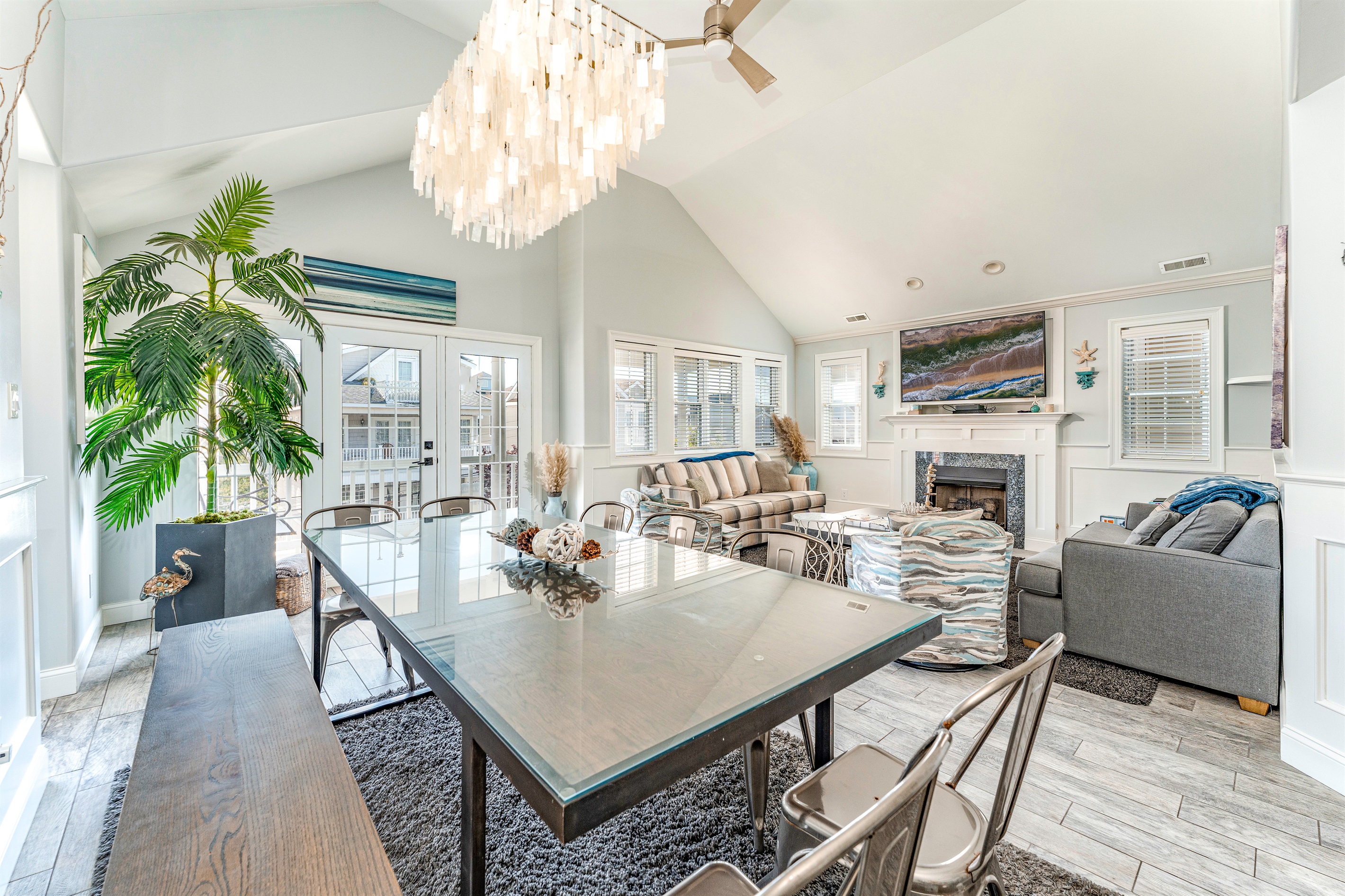 Experience comfort and style in this stunning open-concept living and dining area, complete with a modern chandelier, plush seating, and a cozy fireplace for a perfect retreat.