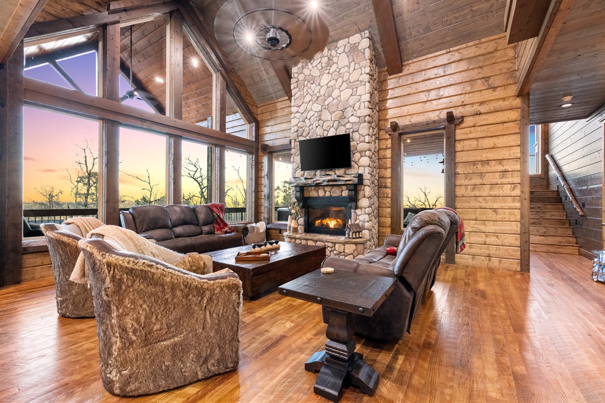 Spacious great room with soaring ceilings, stone fireplace, and panoramic windows
