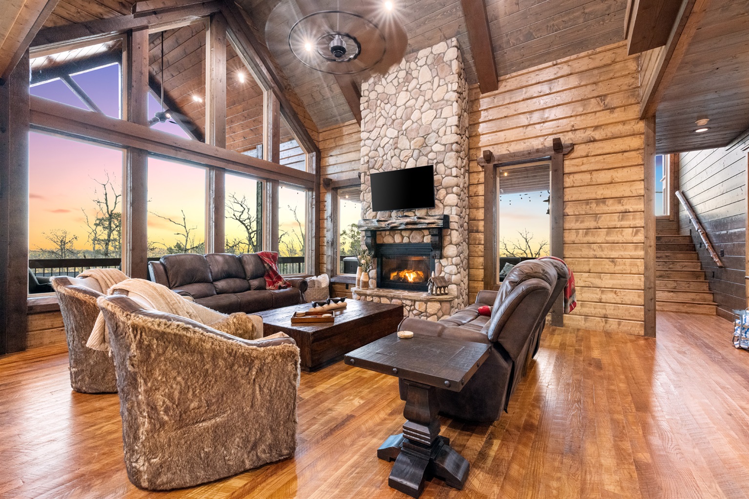 Spacious great room with soaring ceilings, stone fireplace, and panoramic windows